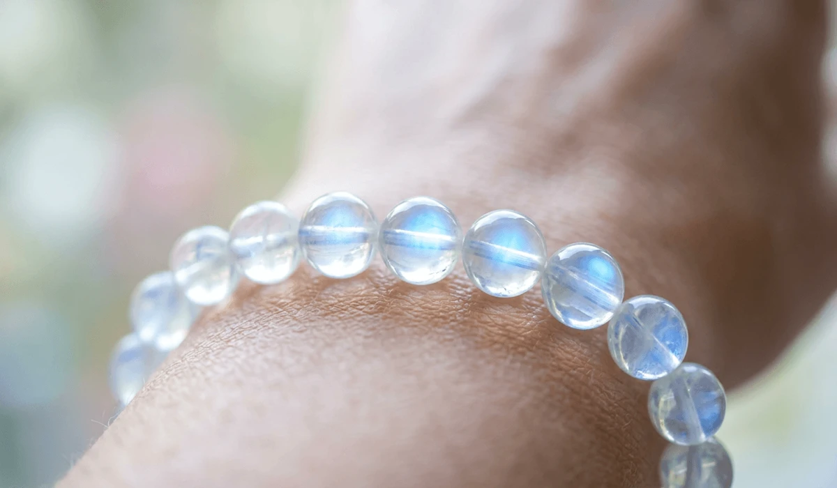 A close-up view of a rainbow moonstone bracelet worn on the left wrist to absorb soothing energy.