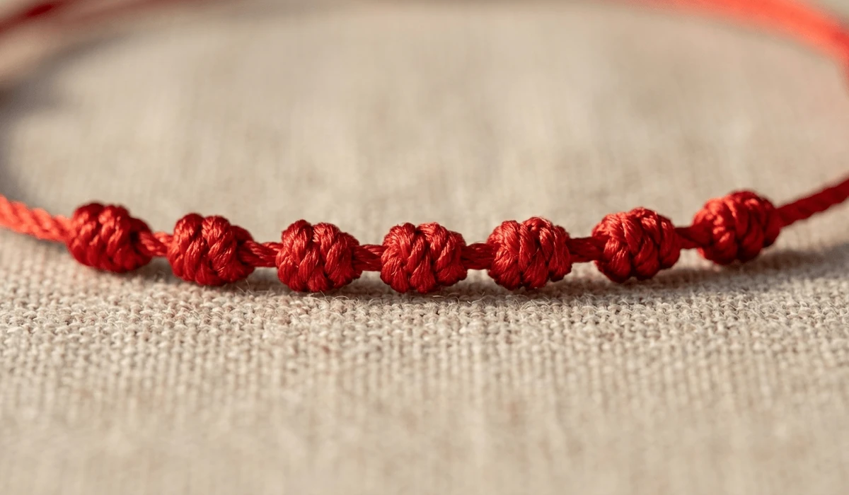 Close-up of a 7-knot red string anklet made of vibrant crimson silk, highlighting the traditional handcrafted knots and spiritual protection symbolism.
