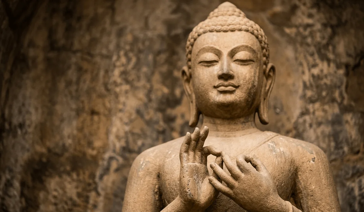 Close-up of a Buddha statue's hand mudra and peaceful face, highlighting the symbolic meaning of the Ushnisha and elongated ears.