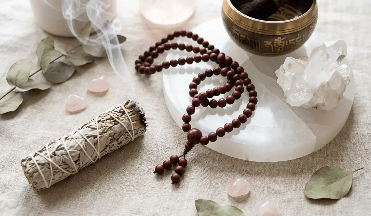 Rosewood mala beads placed on selenite plate with sage smudging smoke for spiritual cleansing ritual.