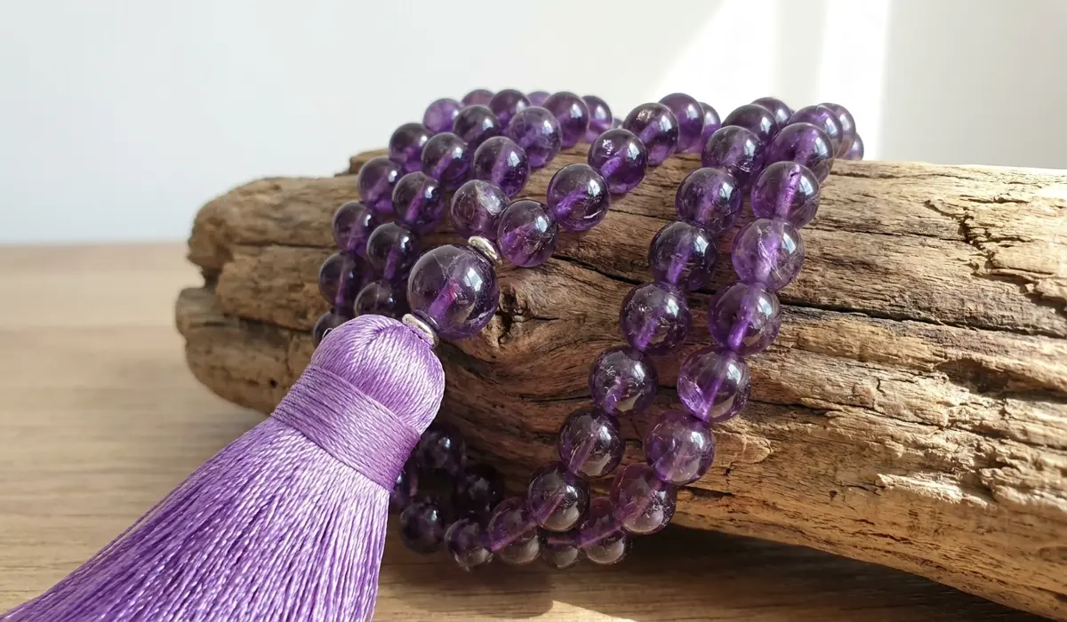 Close-up of a traditional 108-bead Amethyst mala with polished purple gemstones and a silk tassel.