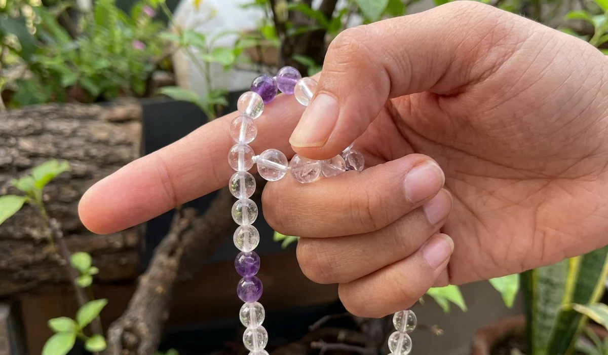 Close-up of the proper mala grip for Japa meditation using the middle finger and thumb while avoiding the index finger.