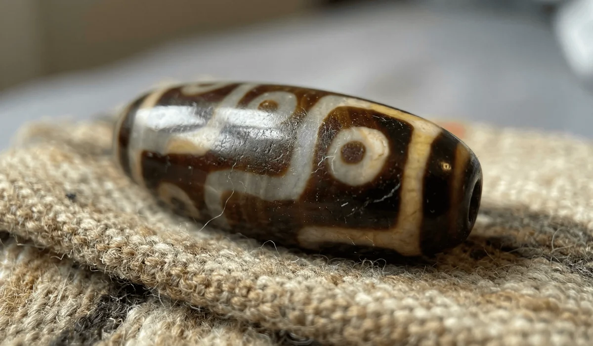 Authentic Tibetan Dzi beads with ivory-white etched eye patterns on dark brown agate stone showing waxy texture.