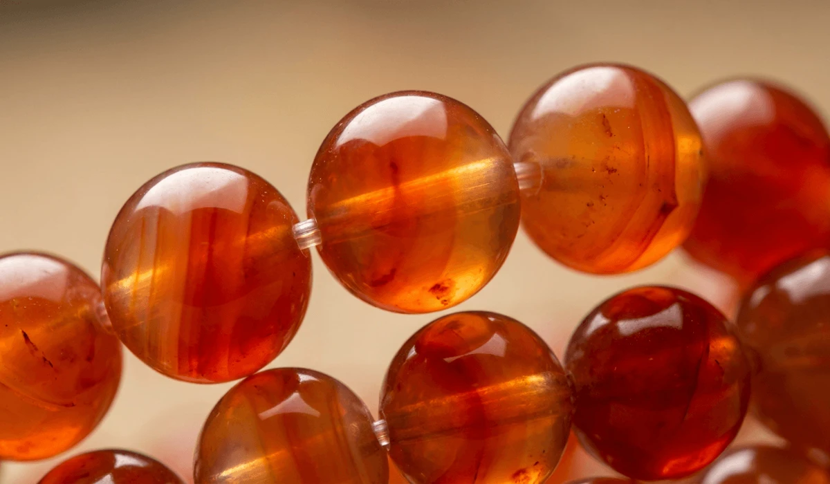 Close-up of natural polished carnelian gemstone beads showing rich orange and red translucent hues.