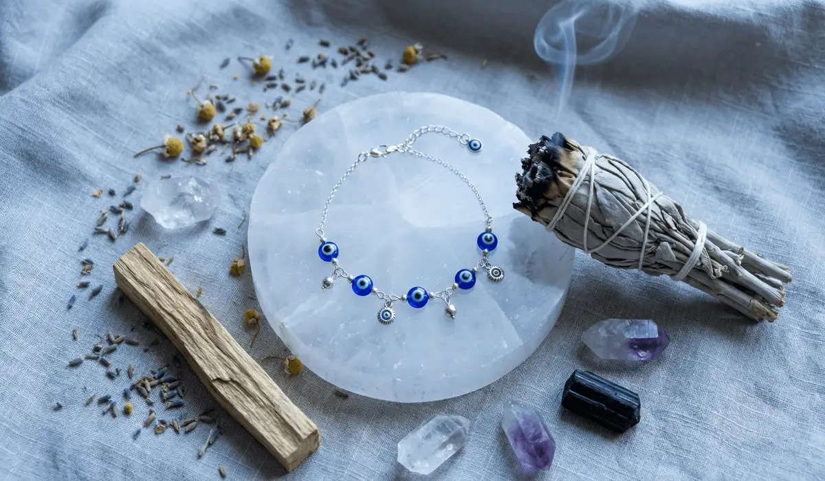 A spiritual cleansing ritual for an evil eye anklet using selenite crystals and sage smoke to clear negative energy.