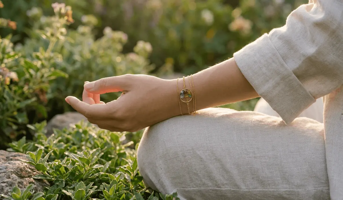 Close-up of a person wearing a natural gemstone Tree of Life bracelet on their left wrist during a morning mindfulness session.