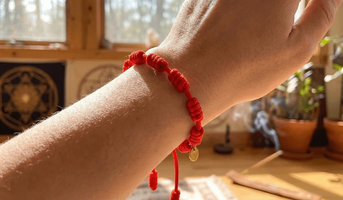 A traditional red string bracelet with seven knots tied on a left wrist, symbolizing spiritual protection and Kabbalah tradition.