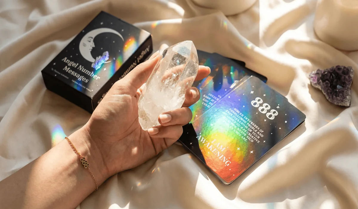 Close-up of spiritual crystal jewelry and an Angel Number oracle deck being used together for manifestation and guidance.