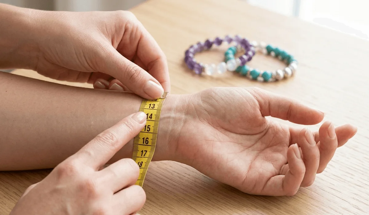 A close-up demonstration of how to measure a wrist for a perfect bracelet fit using a flexible measuring tape.