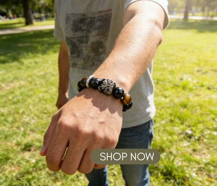 Man wearing the Courage-Awakening Lion Black Obsidian Tiger's Eye Bracelet - The Shield of Bold Fortune in a sunny park, with a "SHOP NOW" button overlay.