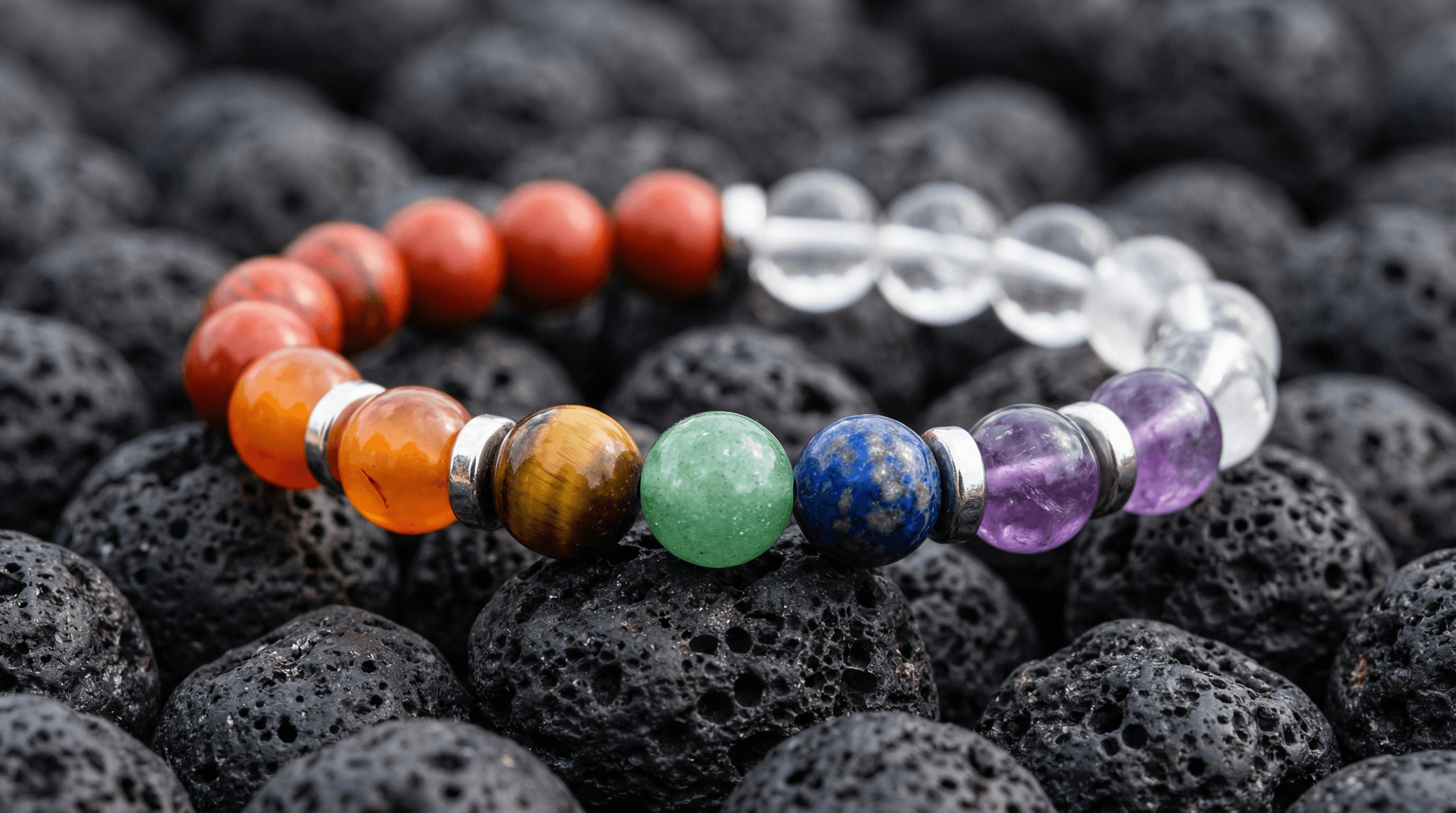 Close-up of a 7 chakra bracelet showing the correct sequence of gemstones from Red Jasper to Clear Quartz on lava stones.
