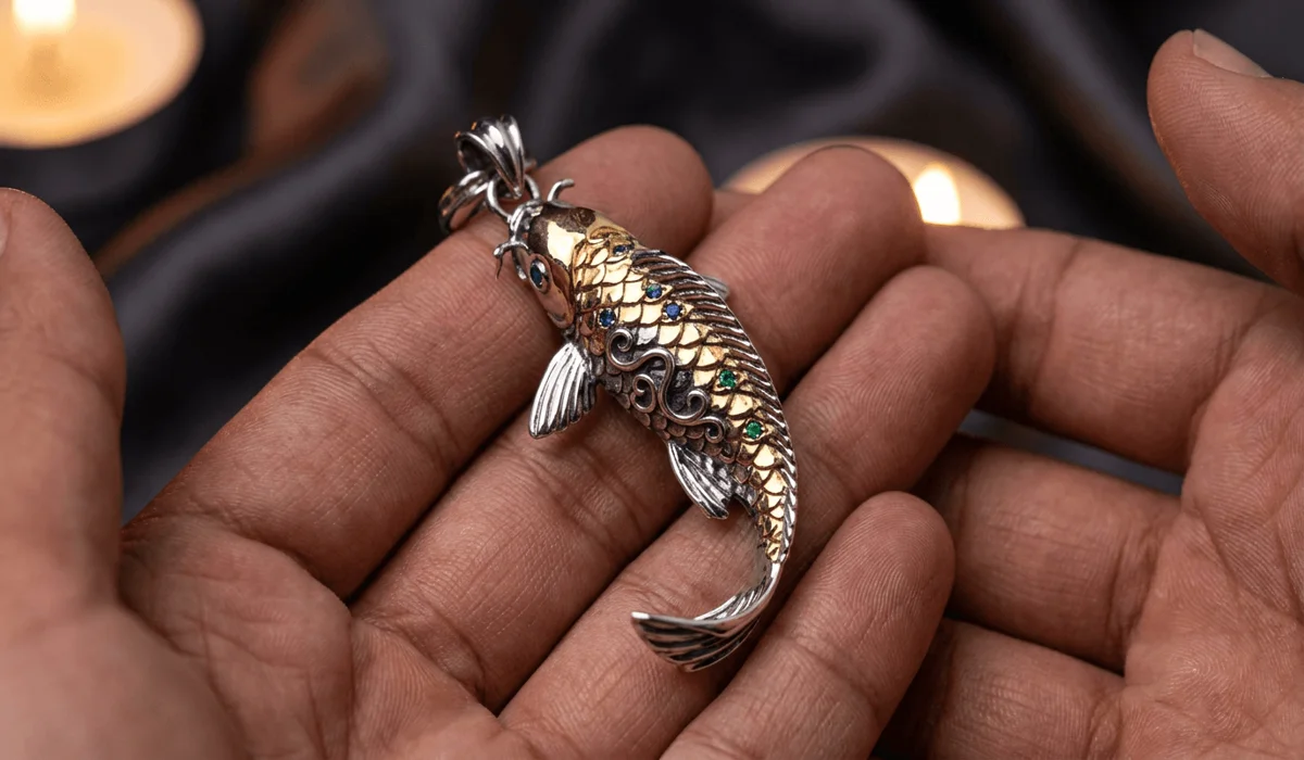 An artisan handcrafted gold and silver koi fish pendant talisman held in hands as a mindfulness anchor.