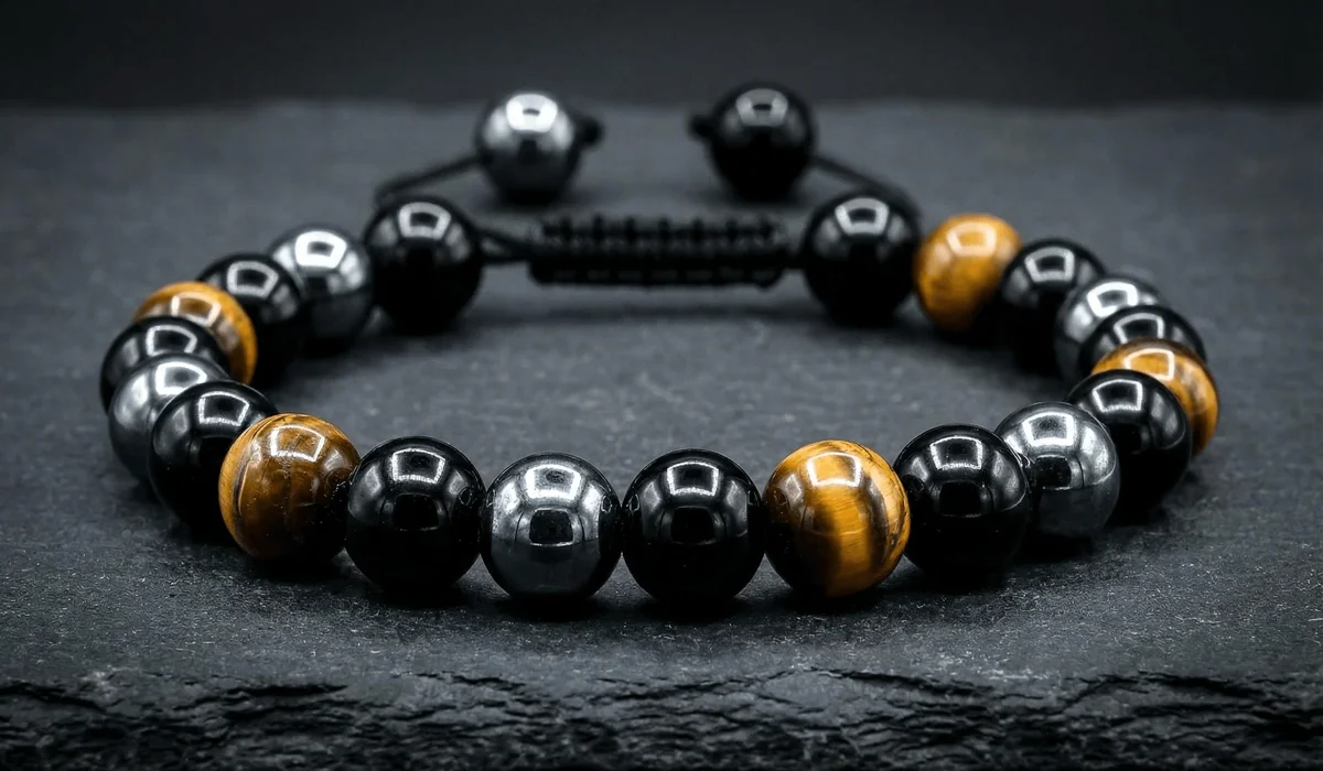 High-quality close-up of a men's triple protection bracelet featuring black obsidian, tiger's eye, and hematite beads on a slate background.