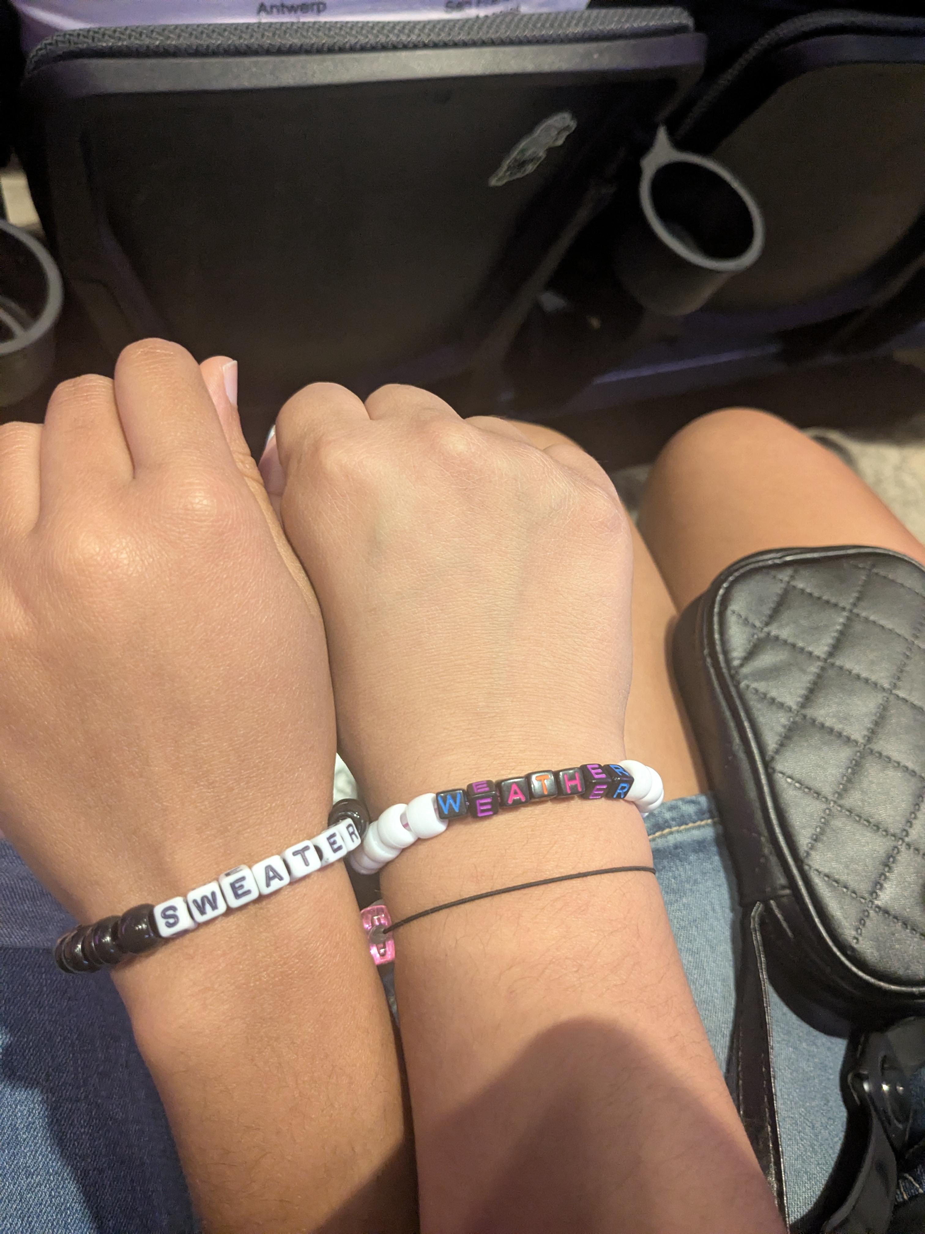Best friends making and wearing matching bracelets for a concert event.