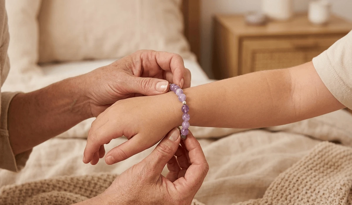 A parent putting a gentle Amethyst crystal protection bracelet on a child's left wrist during a morning ritual.