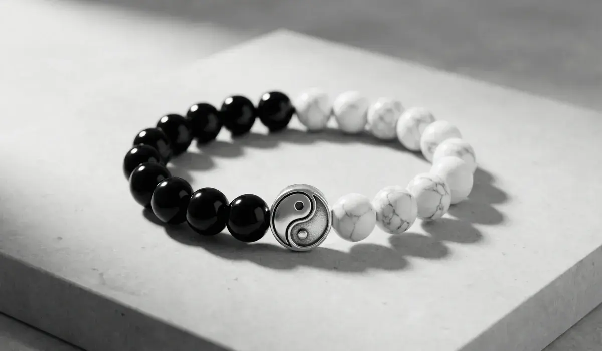 Yin Yang beaded bracelet with polished black obsidian beads, white howlite beads, and a silver Yin Yang charm, displayed on a light gray stone surface for spiritual jewelry and balance-themed content.