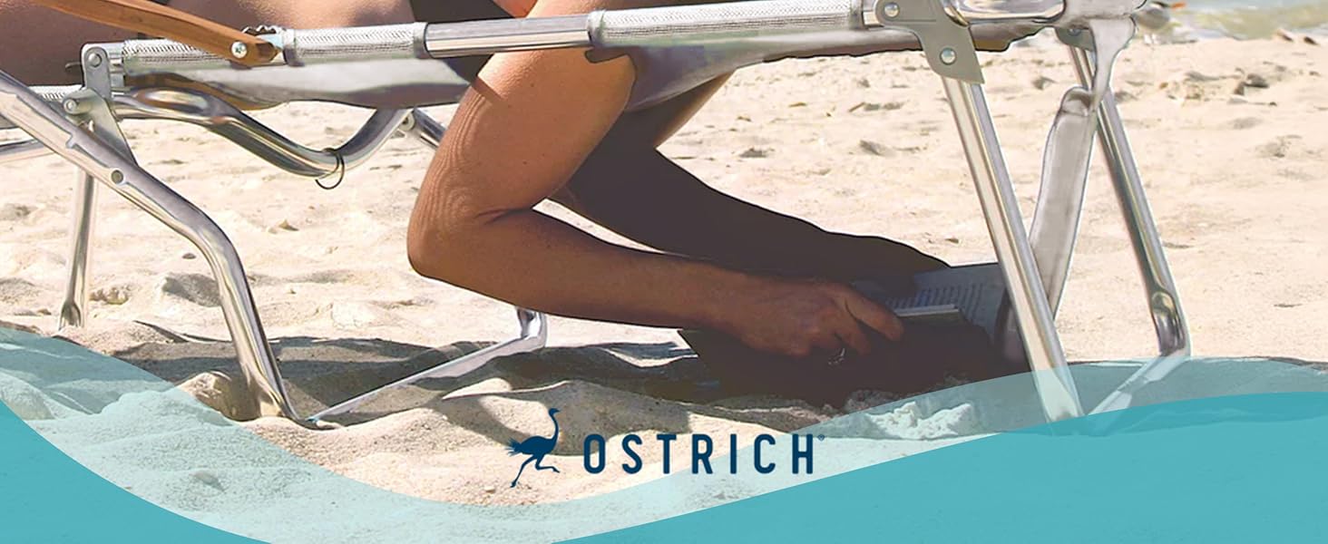 A woman lounges face down on an white beach chair, relaxing under the sun while reading a book.