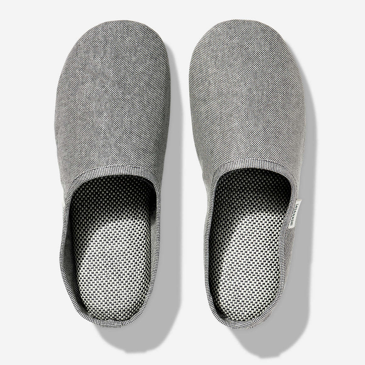 Japanese-style room slippers in light grey color photographed against a white background. Each slipper has Saswashi written on tag near foot opening.
