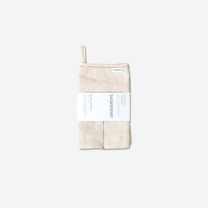 Smooth side of body scrub mitt. Cream colored with red piping. Product label wrapped around middle. Hang tab on top left corner.