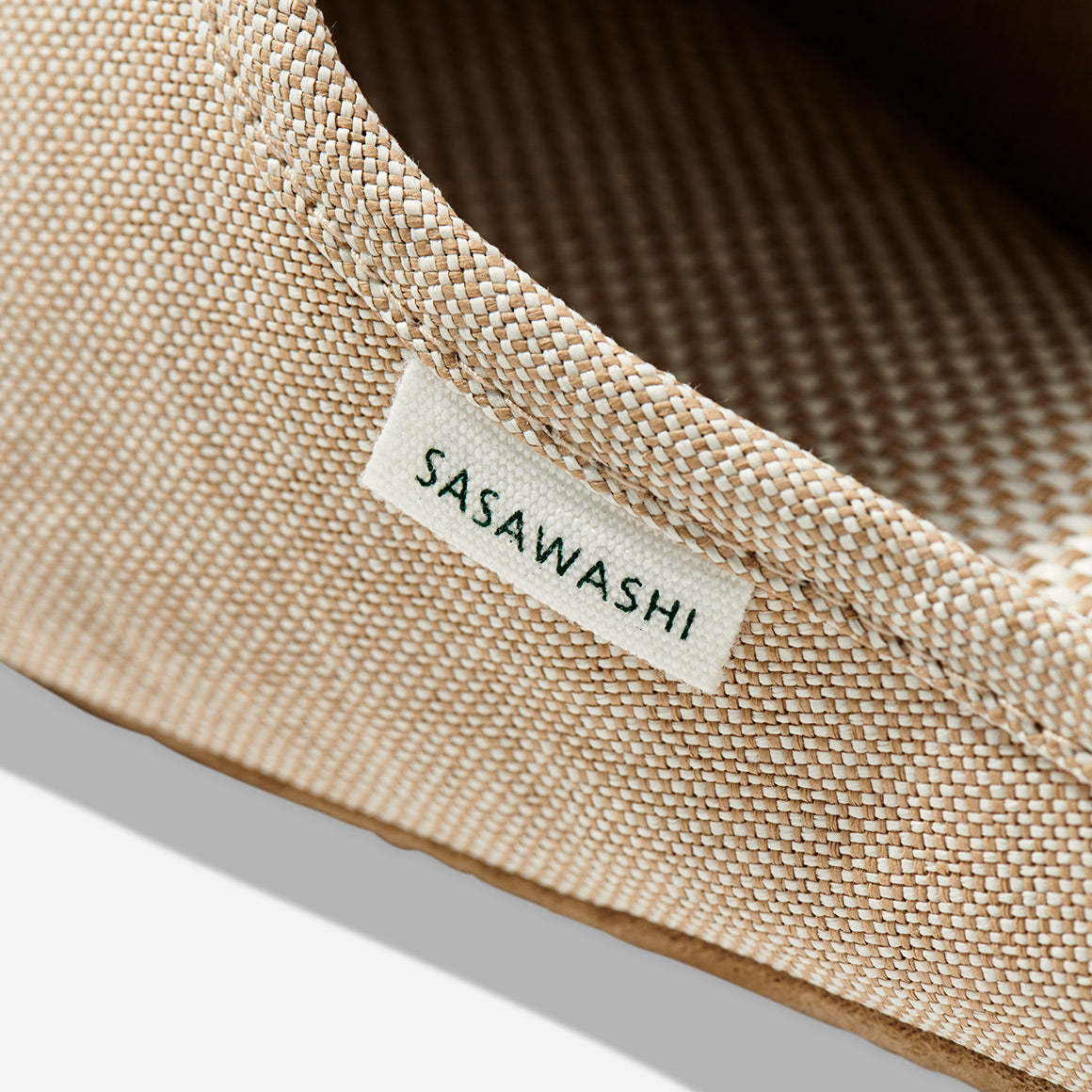 Up-close image of the side of a beige color slipper with Sasawashi written in black on a white tag.