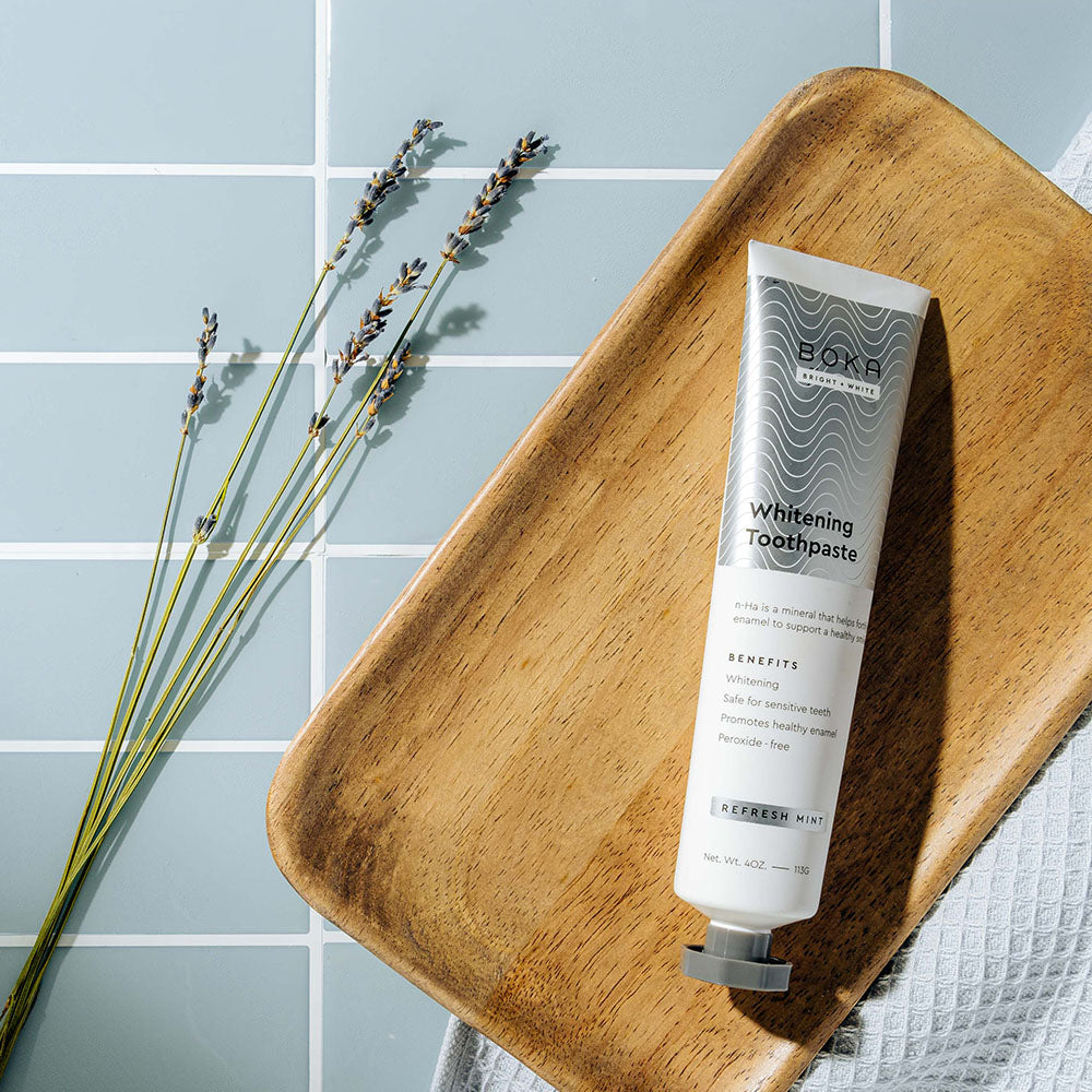 3-pack Nano (n-Ha) Whitening Toothpaste with Refresh Mint on a tray, beside lavender on blue tile.