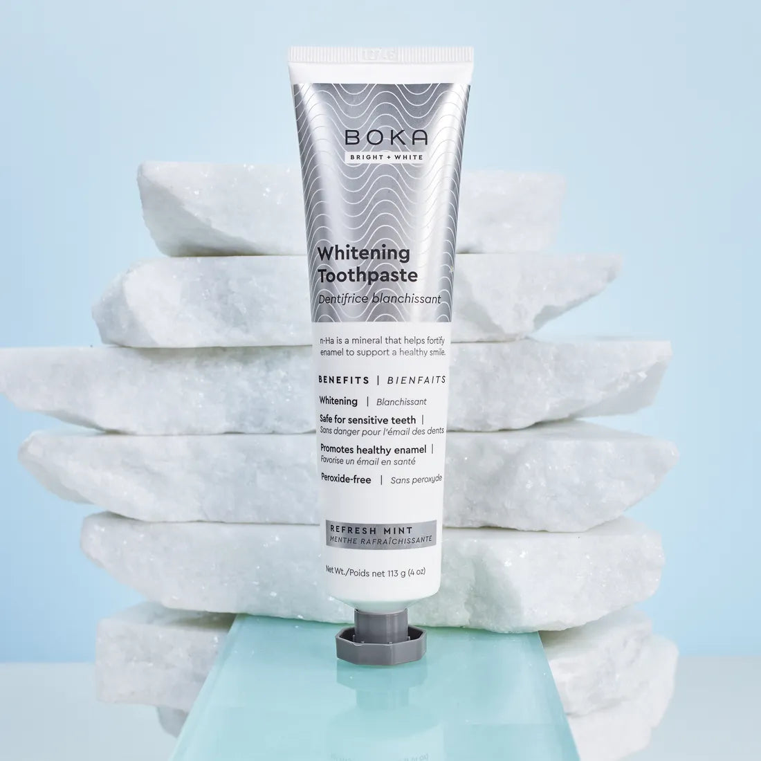 Refresh Mint Whitening n-Ha Toothpaste stands upright before stacked white marble slabs.
