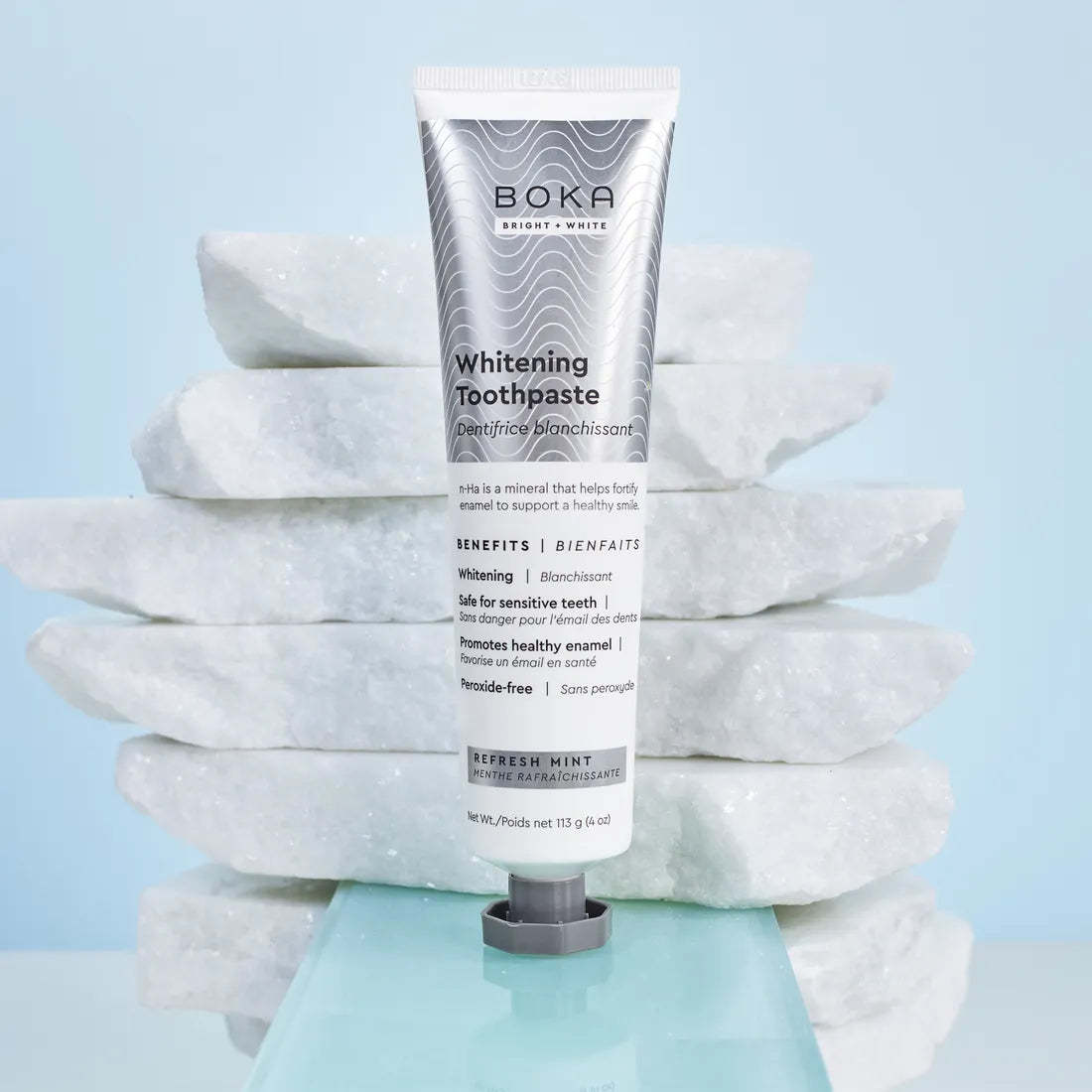 Refresh Mint Whitening n-Ha Toothpaste stands upright before stacked white marble slabs.