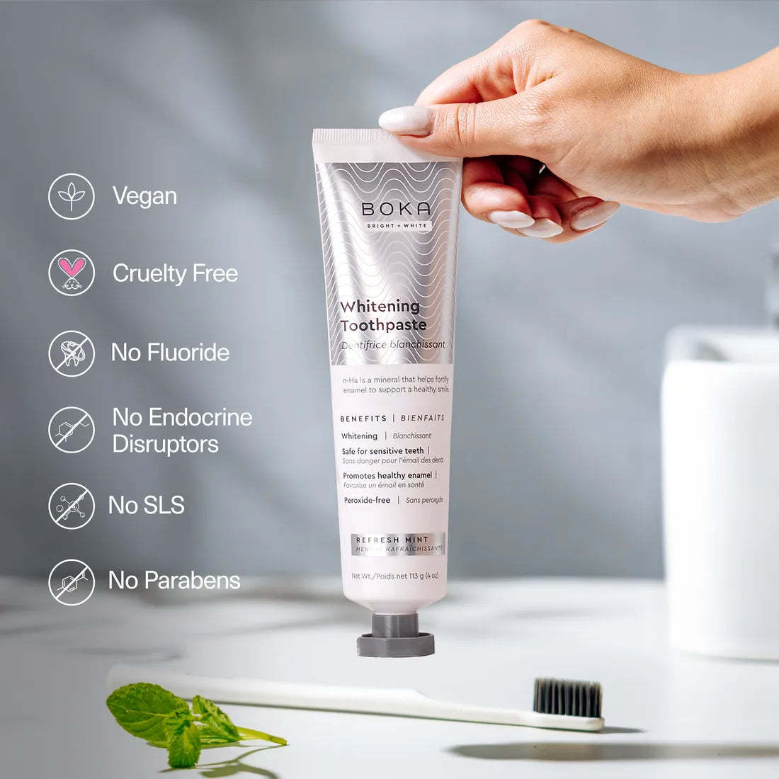 A hand holds Refresh Mint Whitening n-Ha Toothpaste—whitening for sensitive teeth.