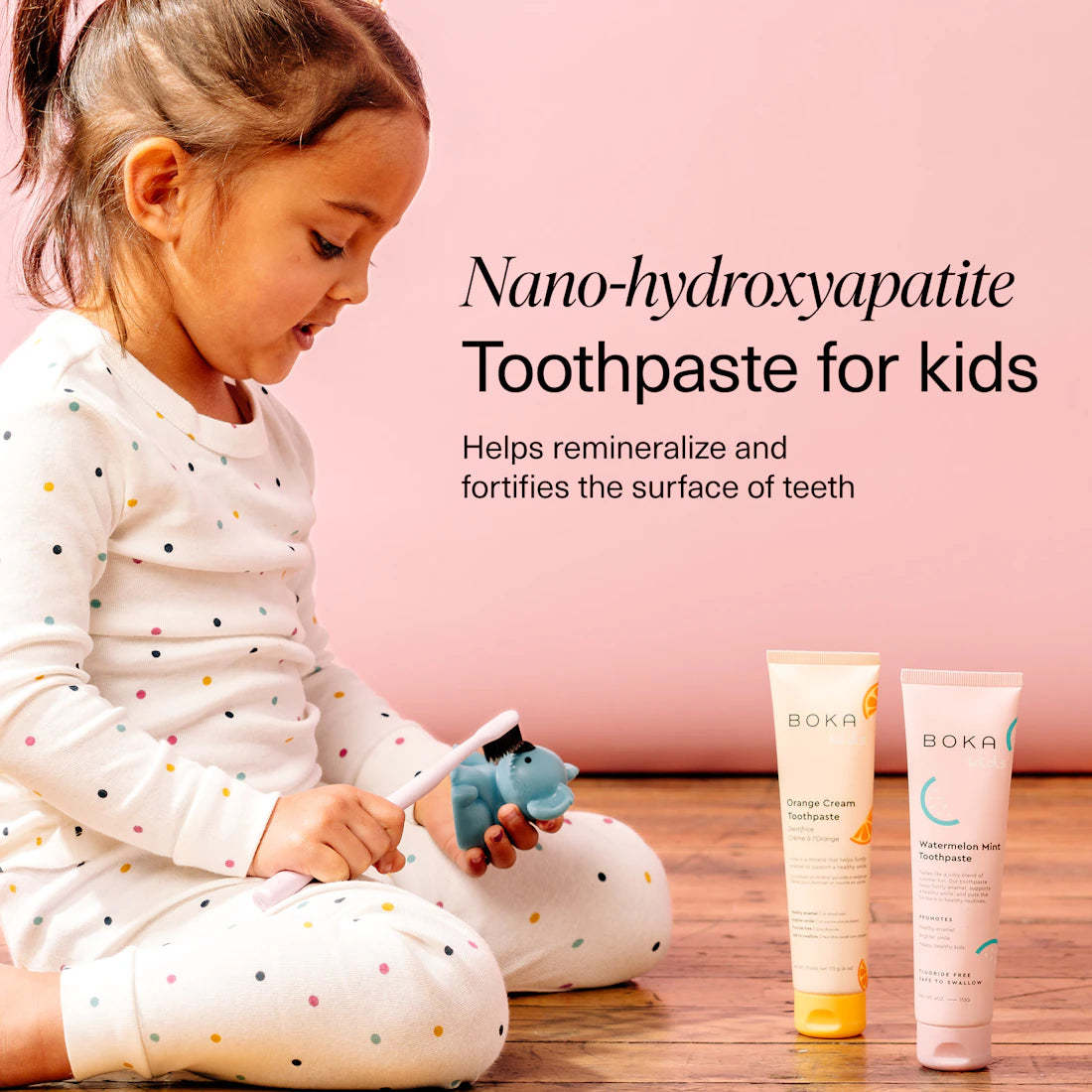 Young child in polka dot pajamas with n-Ha Toothpaste Family 3 Pack, smiling about kid-approved flavors.