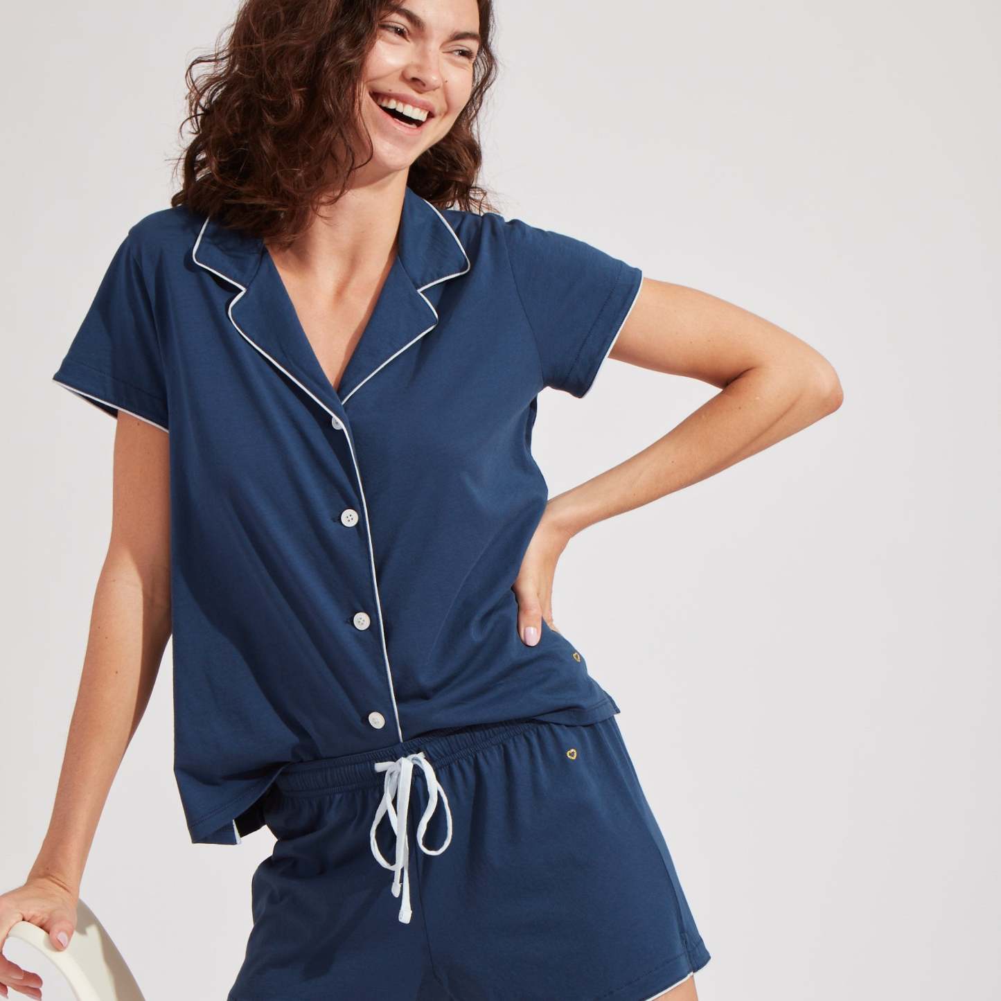 Woman wearing buttery soft navy blue pajama set with white piping.