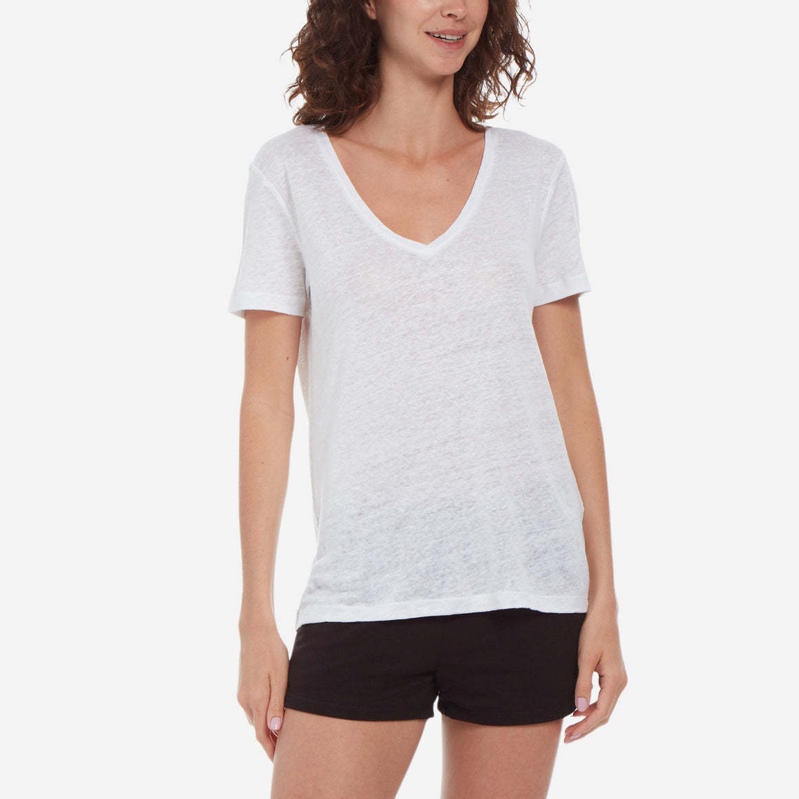 Front-facing model wearing a white linen v-neck tee and black shorts.