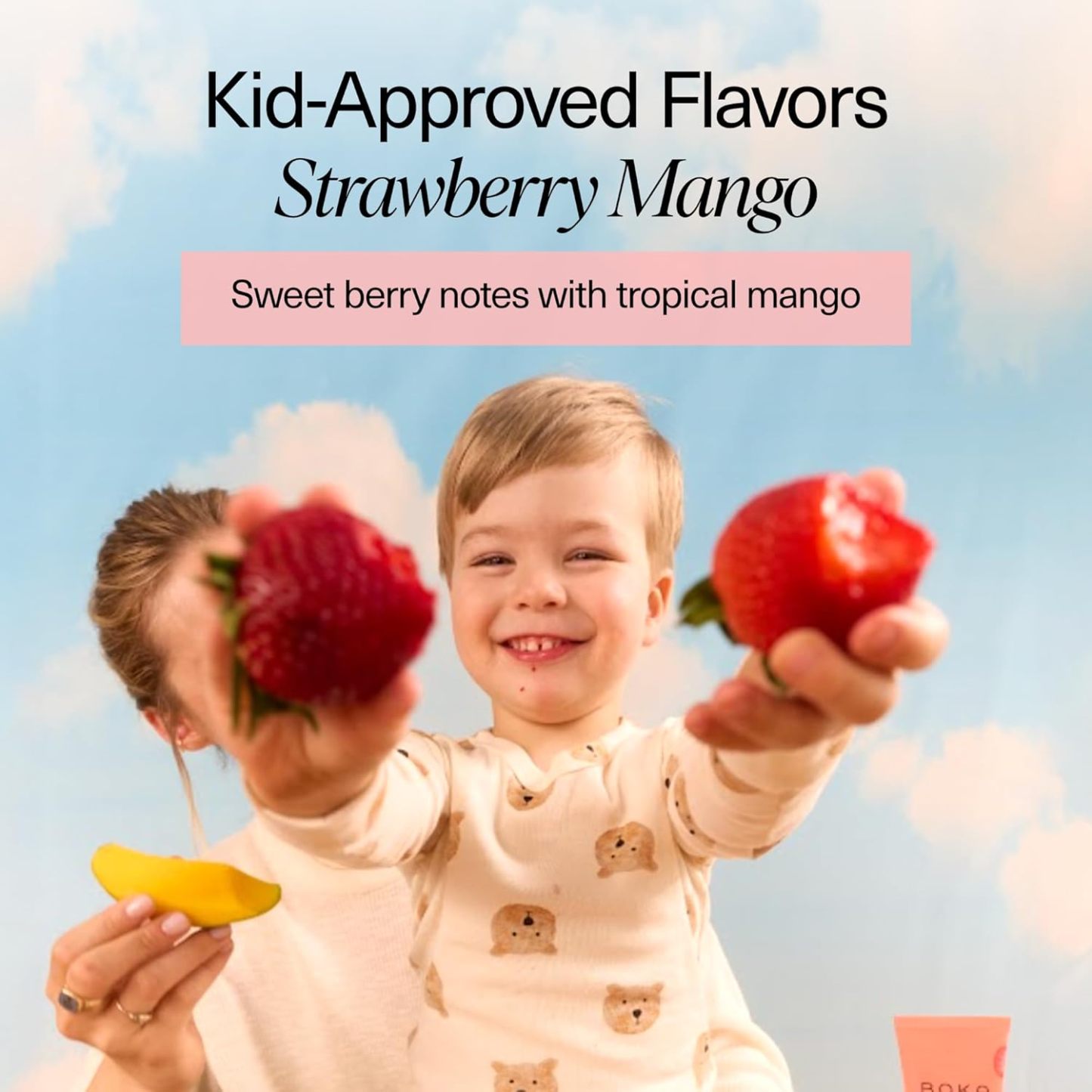 Smiling child holds fruit, excited to use Strawberry Mango n-Ha Toothpaste for brushing fun.