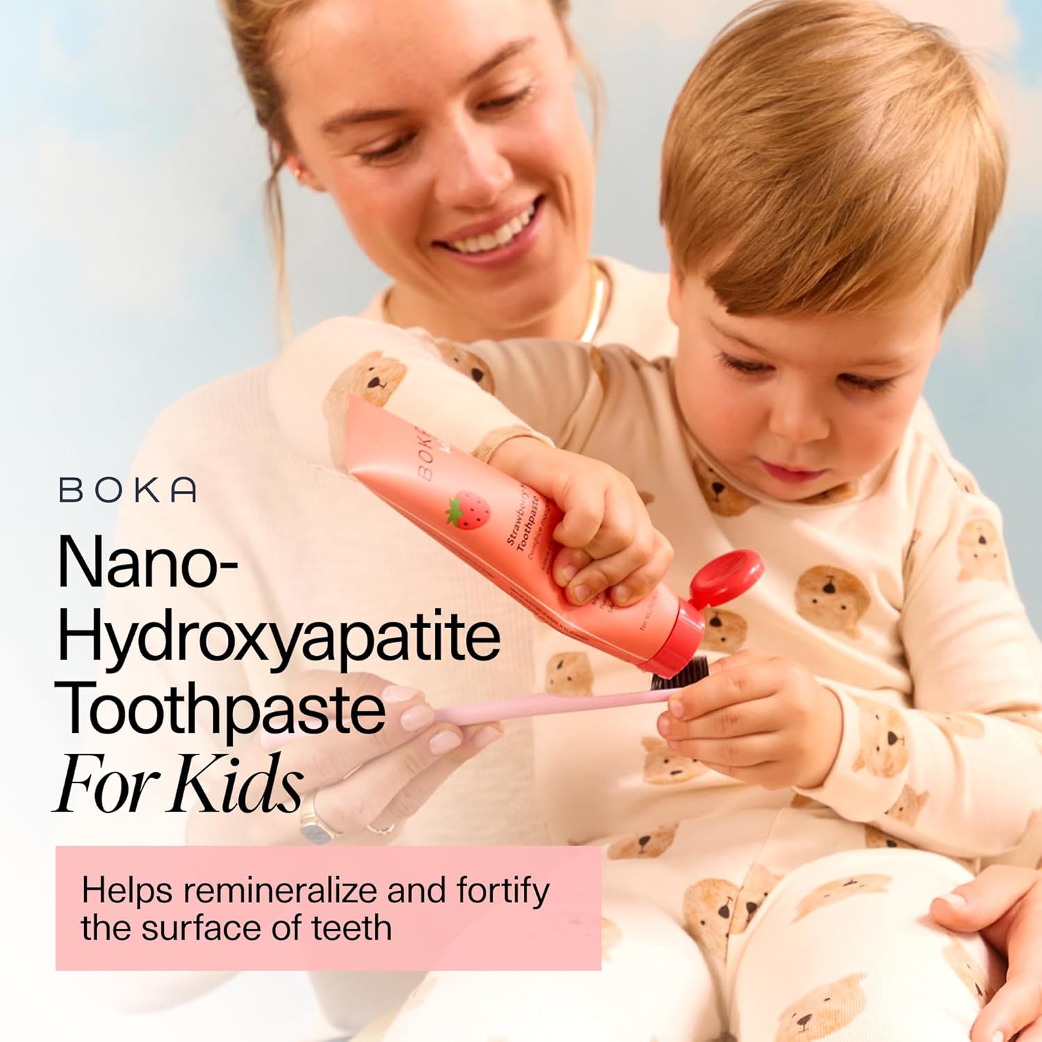 A smiling woman helps a child use Strawberry Mango n-Ha Toothpaste to remineralize teeth.