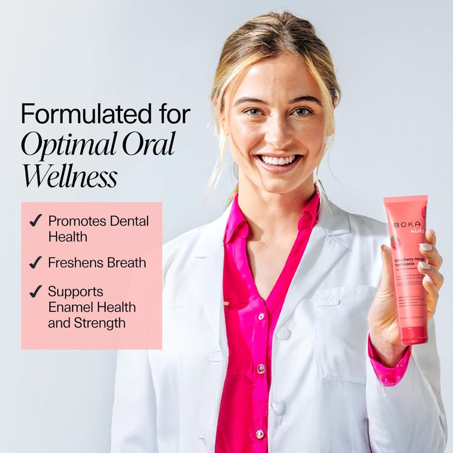 Smiling woman in lab coat holds Strawberry Mango n-Ha Toothpaste; promotes dental health and fresh breath.