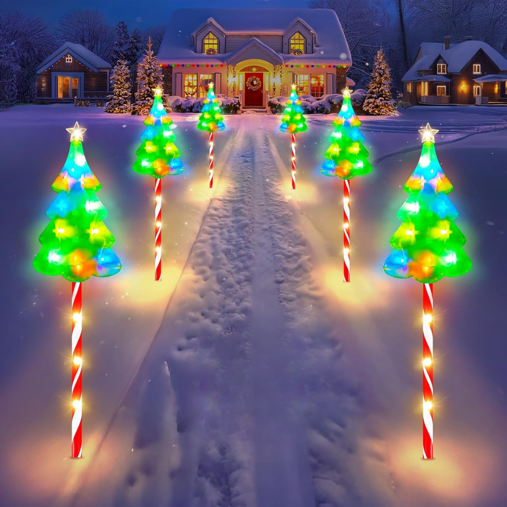 Six solar candy cane Christmas pathway lights with multicolor lit tree toppers staked along snowy driveway at night