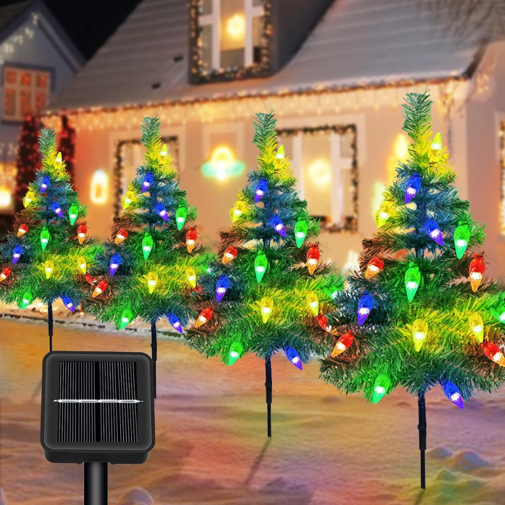 Four solar prelit Christmas tree pathway lights with red and multicolor strawberry-style LED bulbs staked in a row in front of a decorated home