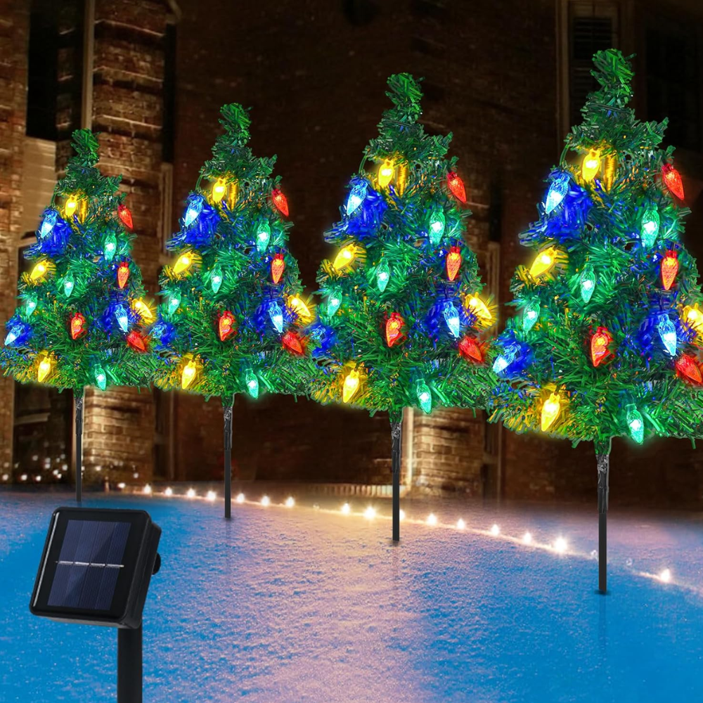 Three solar Christmas tree pathway lights with multicolor LED bulbs staked in snow, solar panel shown, daytime product shot
