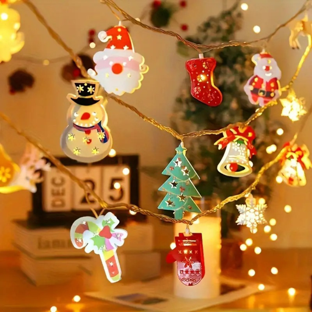 Battery powered Christmas LED string lights with holiday character pendants including snowman, Santa, tree, and bell figures strung near a Christmas tree