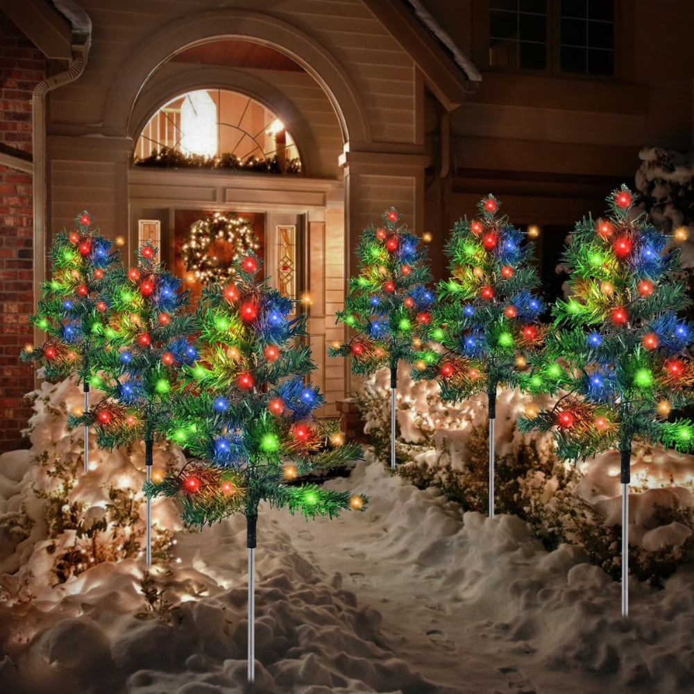 Six solar Christmas tree pathway lights with multicolor LEDs staked along a snow-covered walkway leading to a lit front door