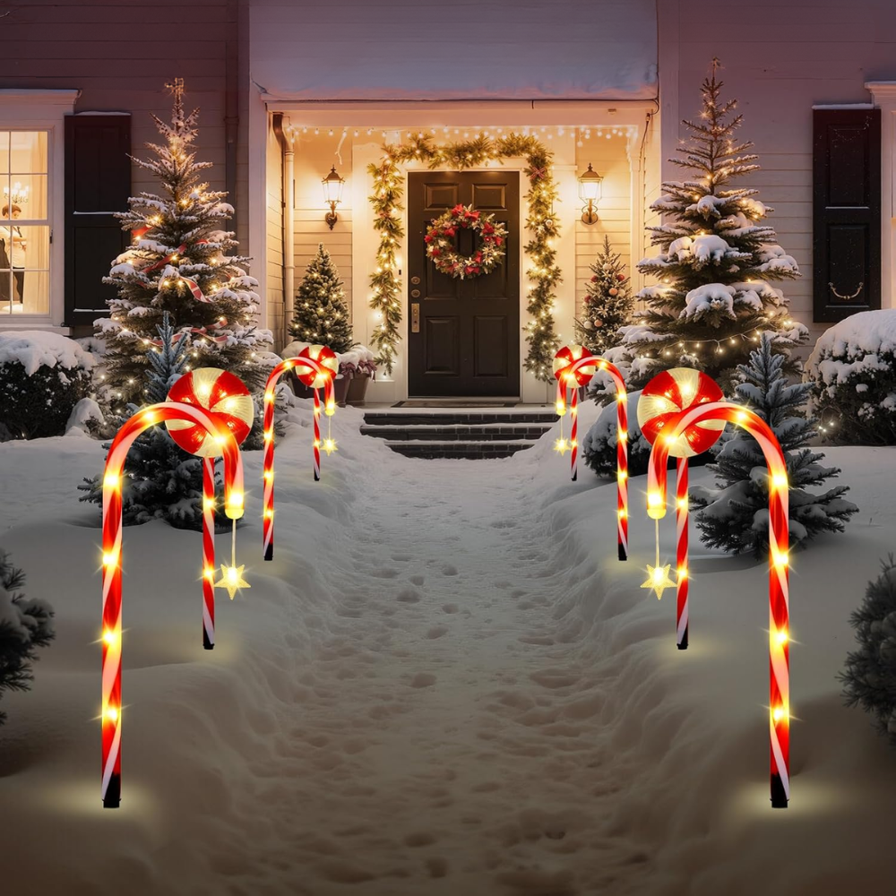 Solar candy cane and peppermint Christmas pathway lights flanking snowy front door walkway at dusk