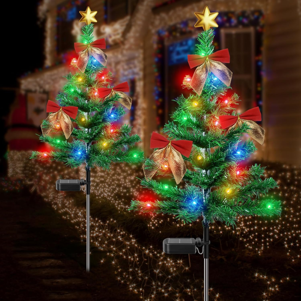 Solar Christmas tree pathway lights with star topper, red bows, and multicolor LED bulbs staked beside a holiday-lit house at night