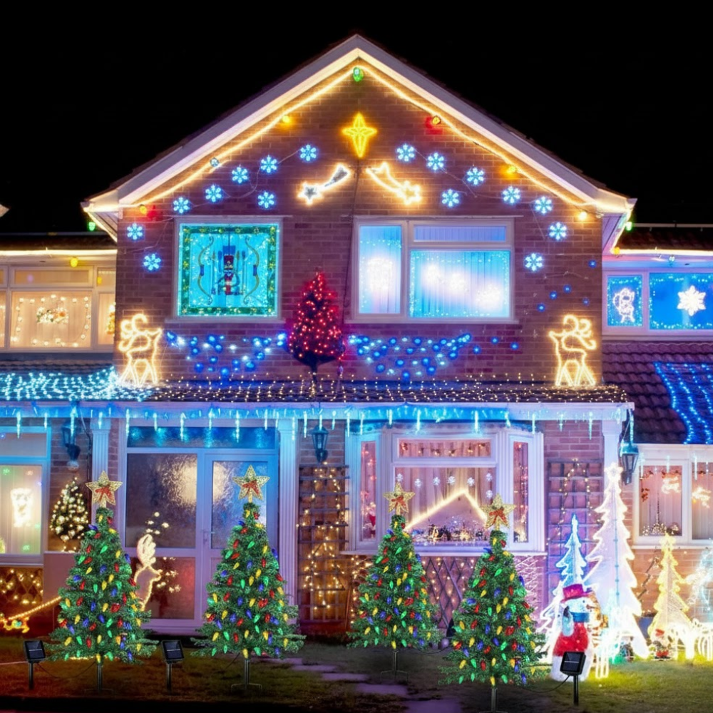 Solar Christmas tree pathway lights visible as part of a full outdoor holiday display covering an entire lit house facade at night