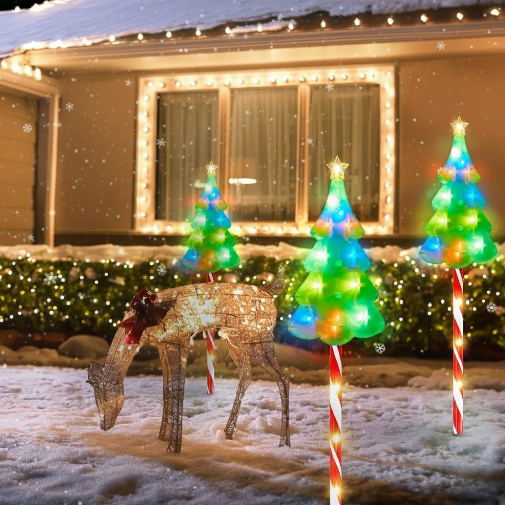 Solar candy cane Christmas pathway lights with tree topper beside a lit reindeer decoration in snowy yard