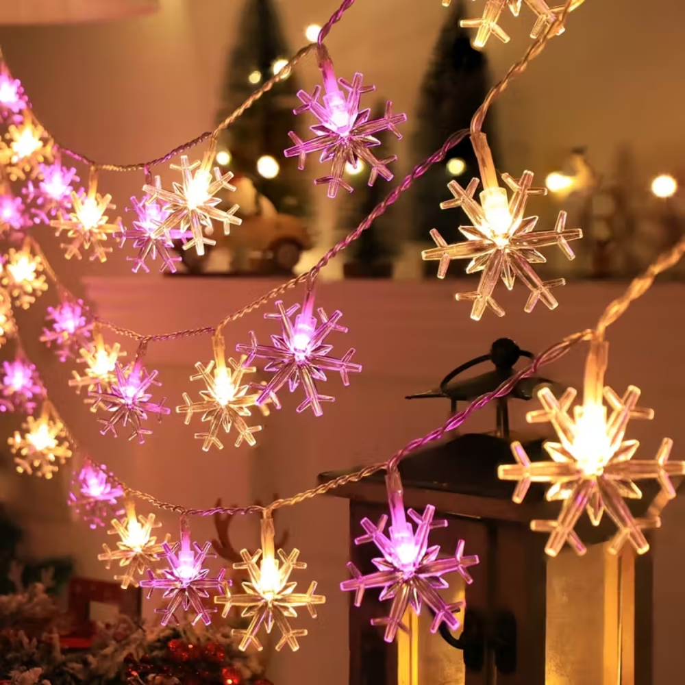 Snowflake LED string lights in pink and warm white draped on a shelf with a decorative bird figurine