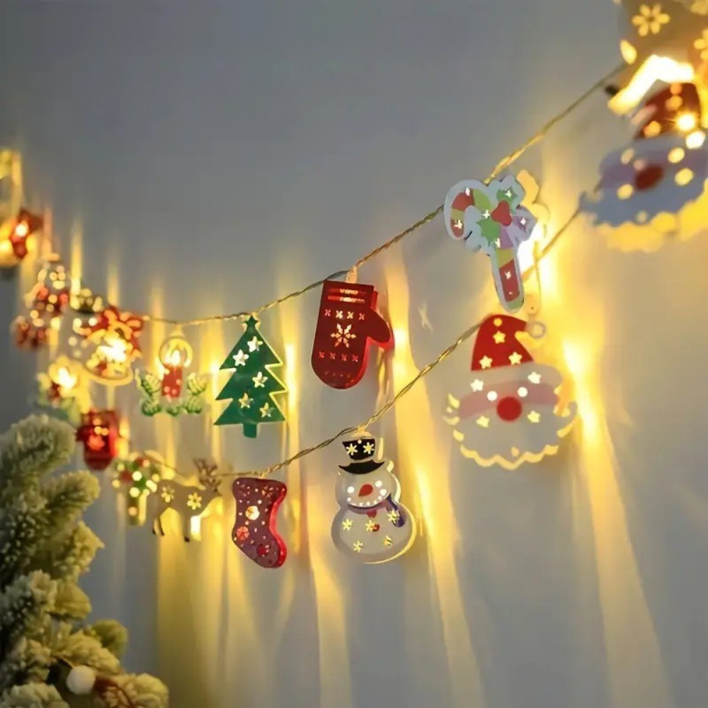 Battery powered Christmas LED string lights showing holiday character pendants including glove, tree, snowman, and stocking figures lit against a warm background