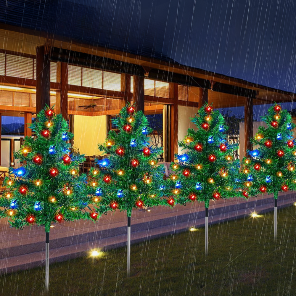 Eight solar Christmas tree pathway stake lights with red, blue, and multicolor LED bulbs glowing along a rain-wet patio fence at night