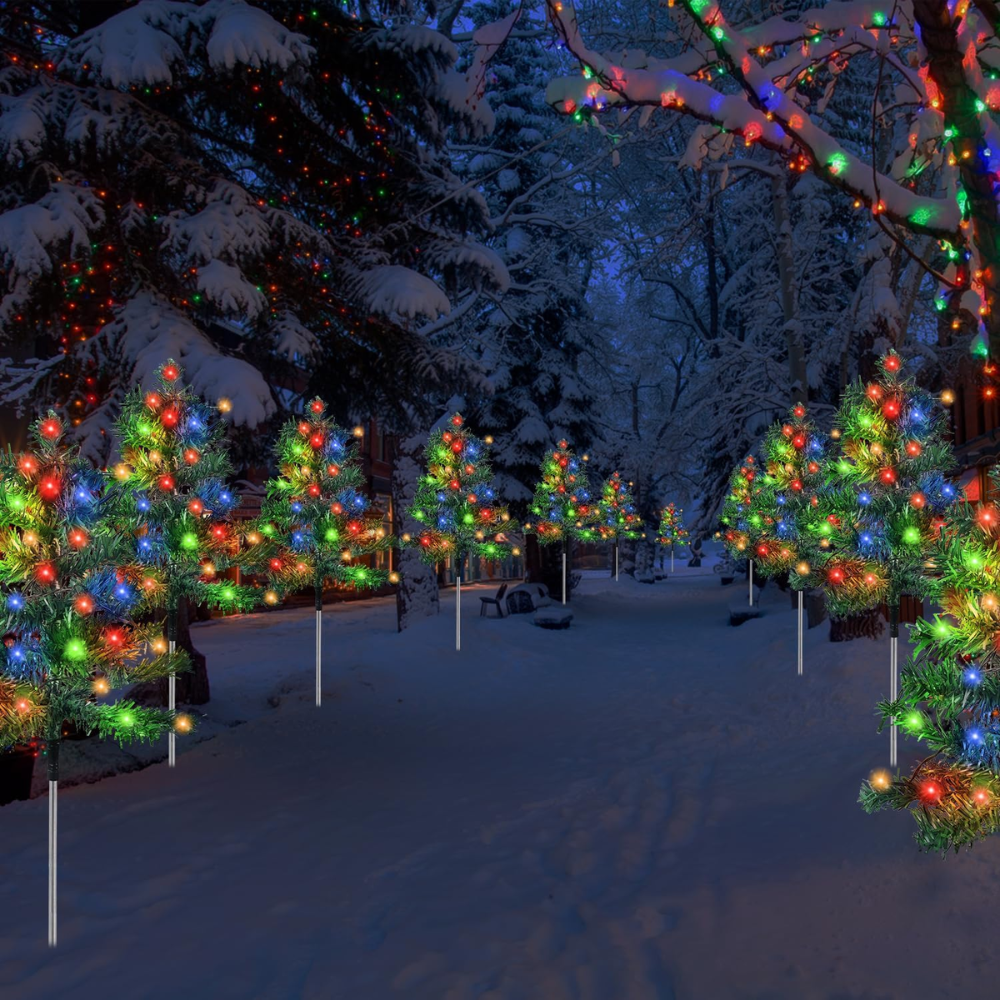 Six solar Christmas tree pathway lights with multicolor C6 LEDs staked in a snow-covered outdoor garden bordered by bare winter trees