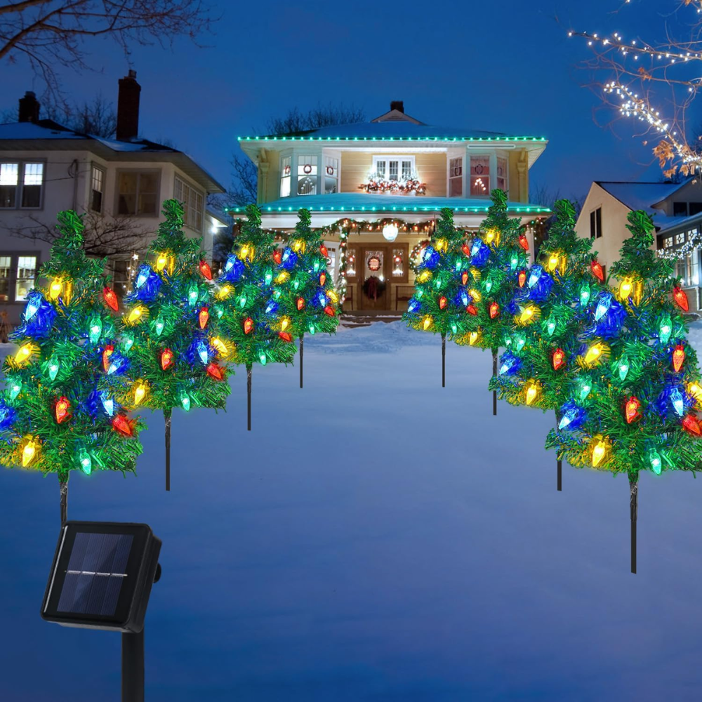 Pack of 4 solar Christmas tree pathway lights with multicolor LED bulbs arranged symmetrically along a snowy driveway in front of a festively lit home
