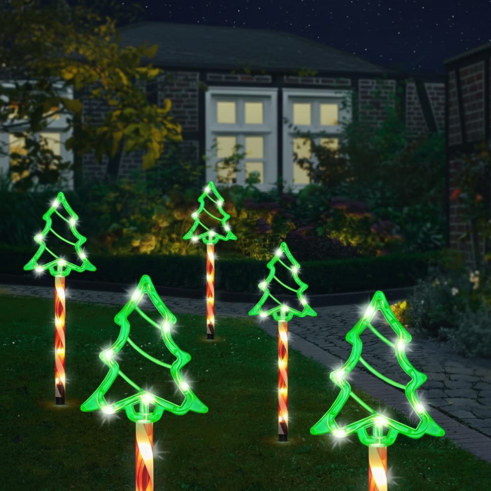 Solar Christmas pathway lights with green tree outline toppers on striped poles glowing at night, illuminated against a garden fence and house