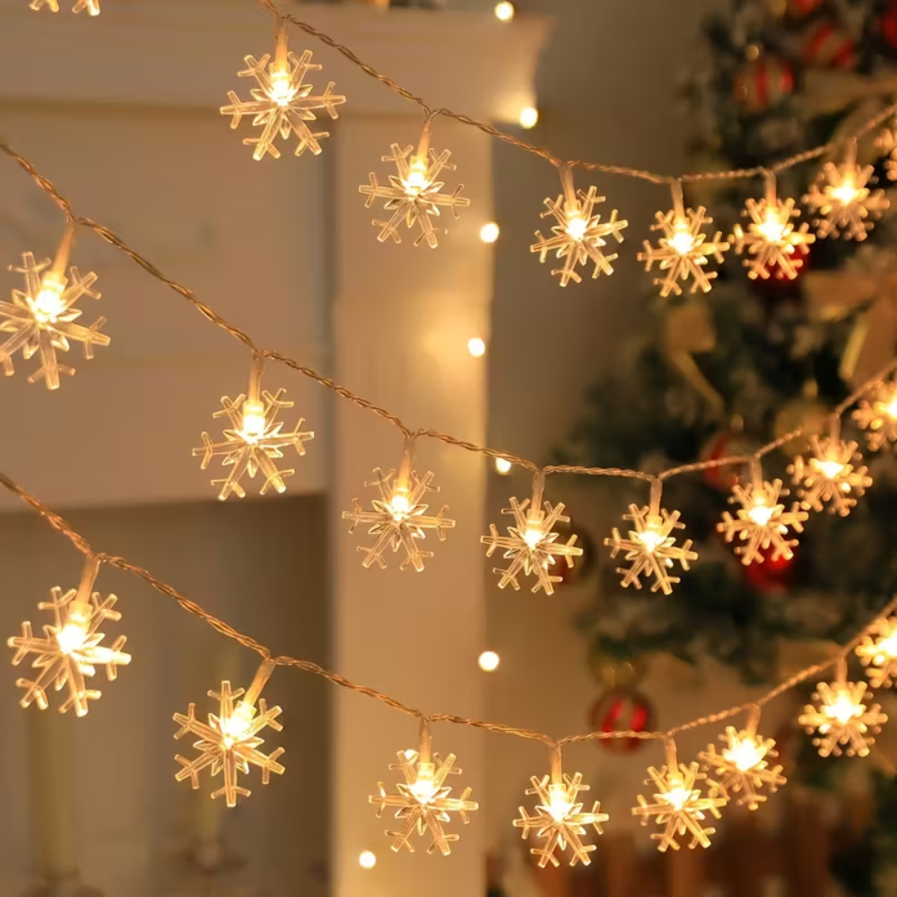 Snowflake LED string lights in warm white draped over Christmas tree branches in indoor holiday setting